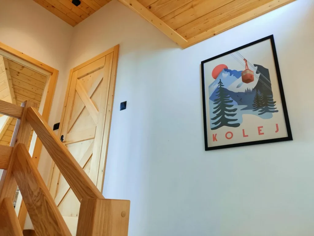 Drewniana balustrada i górskie grafiki na piętrze